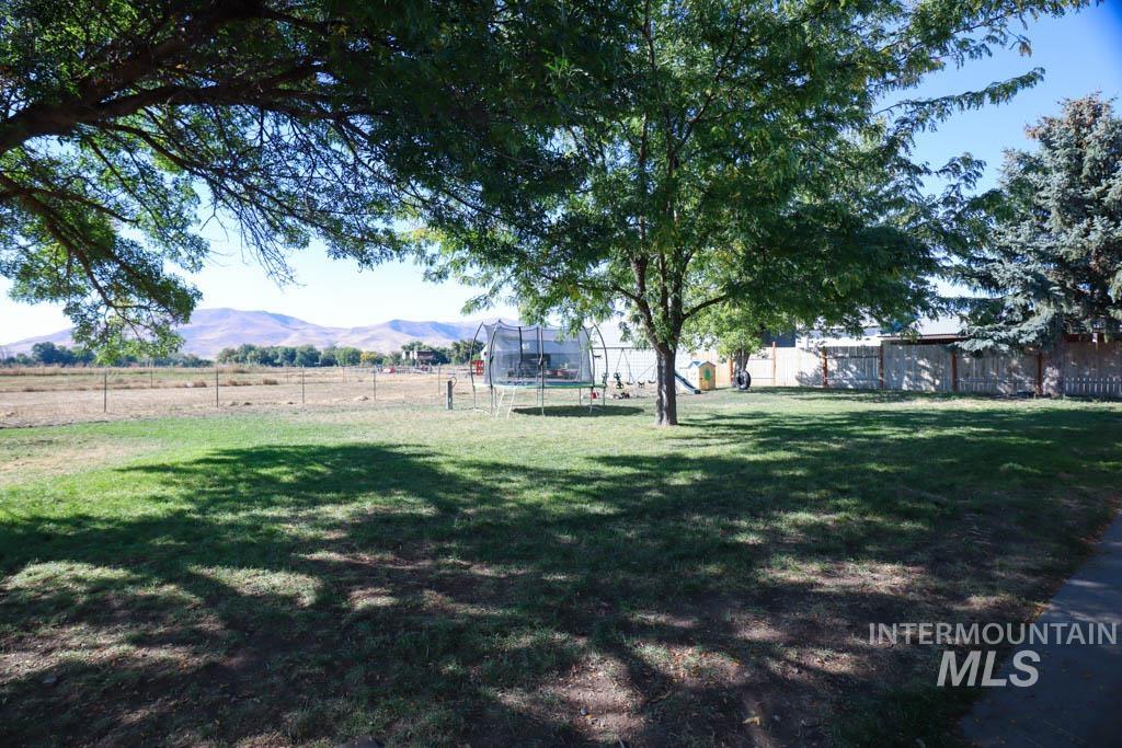 815 Eaton Road Weiser, ID 83672 - Photo 36 of 50 Fenced backyard with a mountain view, a trampoline, and a view of countryside