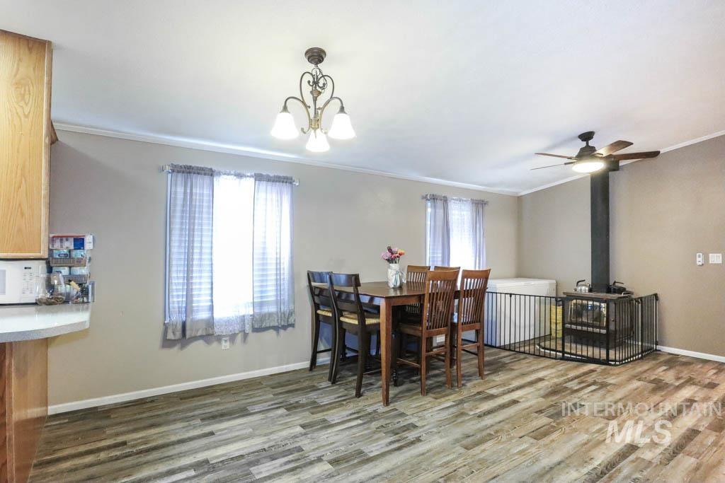 815 Eaton Road Weiser, ID 83672 - Photo 10 of 50 Dining space with ornamental molding, a wood stove, wood finished floors, and a ceiling fan