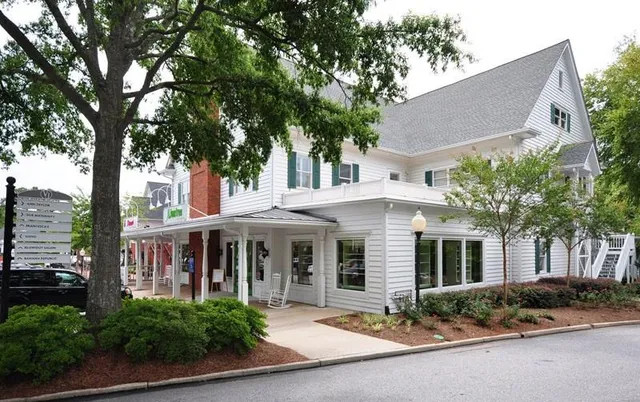 a front view of a house with a garden and trees