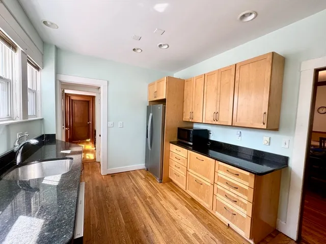 a kitchen with granite countertop a sink and wooden cabinets