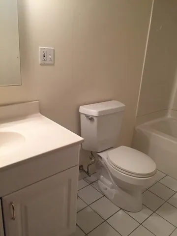 a white toilet sitting next to a bathroom sink and vanity