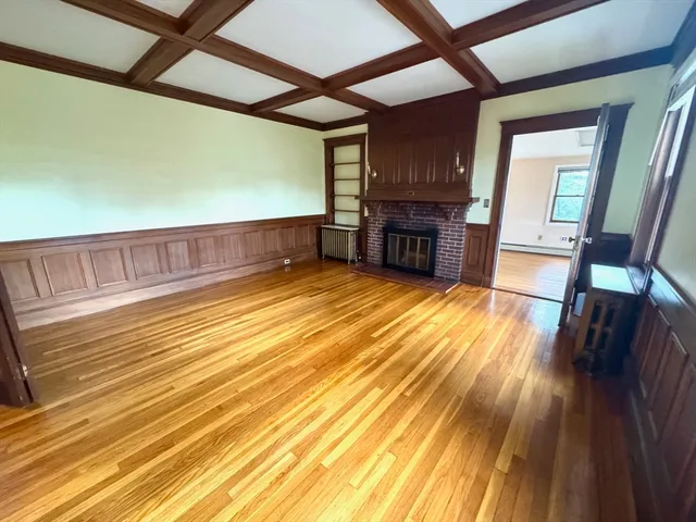 a view of an empty room with wooden floor and a ceiling fan