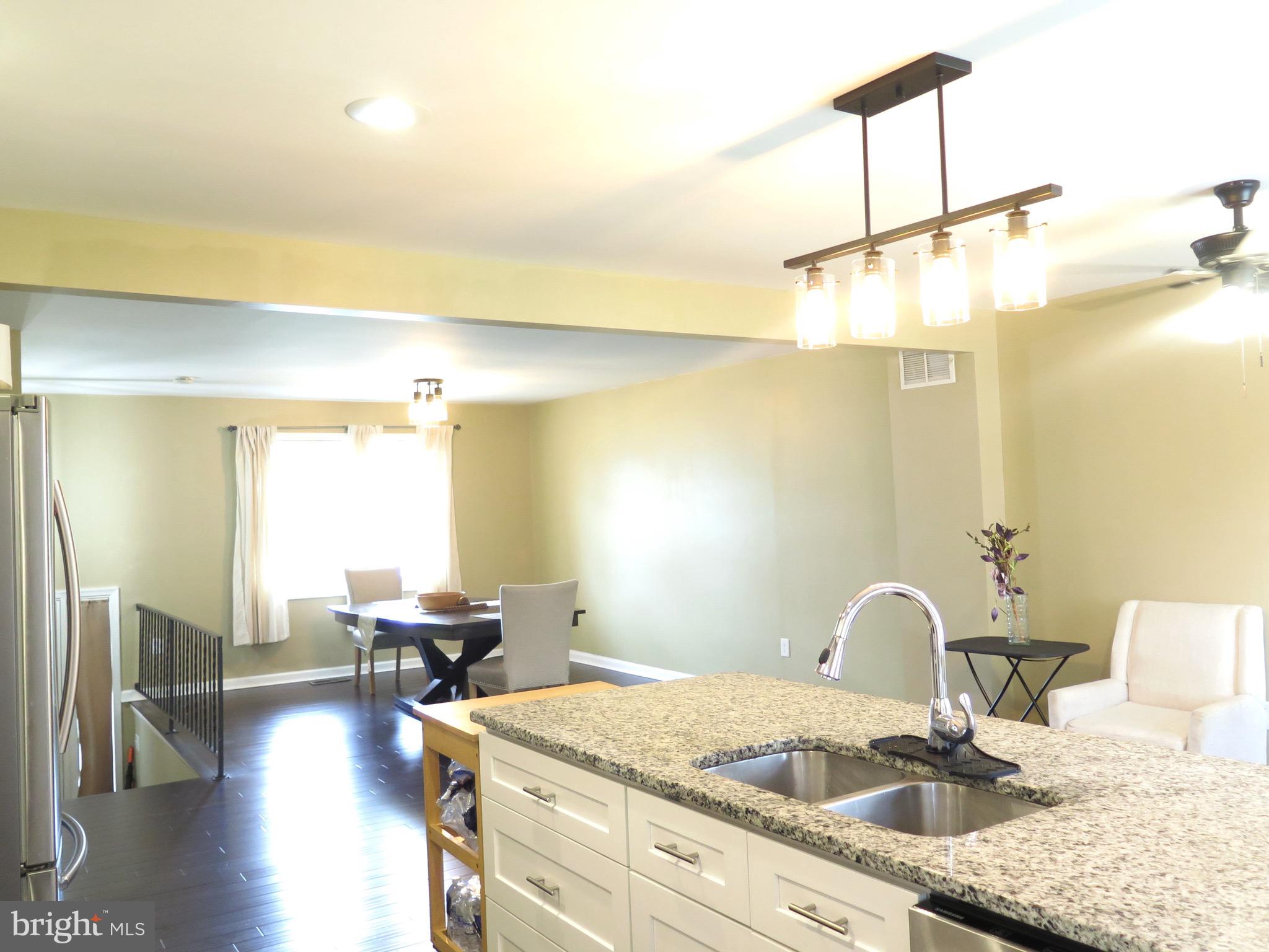 3939 Nemo Road Randallstown, MD 21133 - Photo 4 of 31 a kitchen with a sink dishwasher a dining table and chairs with wooden floor