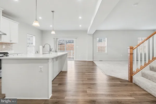 a large white kitchen with a large island oven a sink stainless steel appliances and cabinets