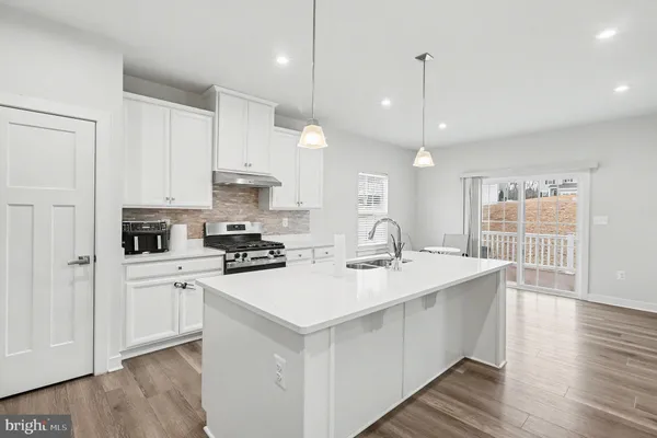a kitchen with a sink a stove a refrigerator and white cabinets