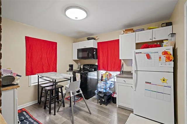 a white kitchen with a refrigerator and a stove top oven