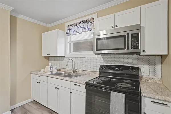 a kitchen with white cabinets and black appliances