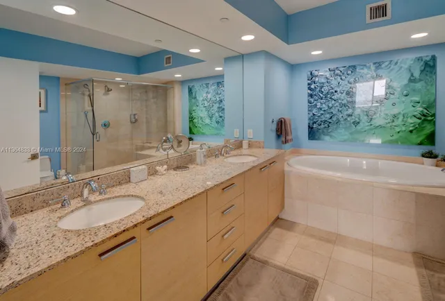 a bathroom with a granite countertop sink mirror bathtub shower and natural light