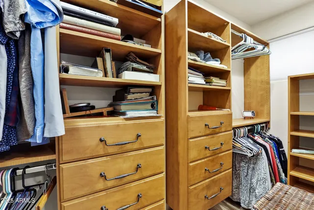 a view of walk in closet with clothes and shoes
