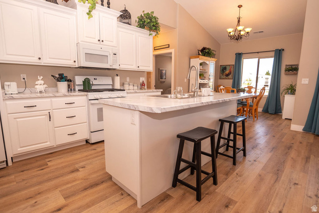 745 East 885 North Beaver, UT 84713 - Photo 14 of 50 Kitchen featuring a kitchen island with sink, white appliances, light countertops, a kitchen breakfast bar, and white cabinetry