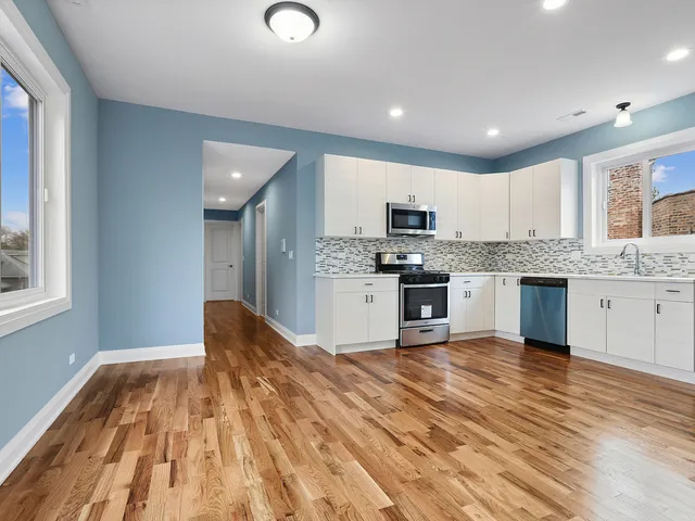a large kitchen with cabinets wooden floor and stainless steel appliances