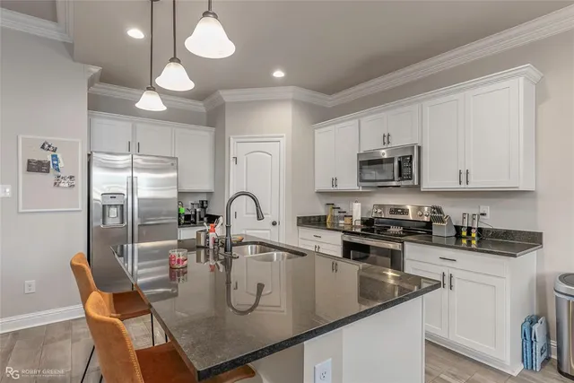 a kitchen with stainless steel appliances granite countertop a sink a stove a refrigerator cabinets and chairs