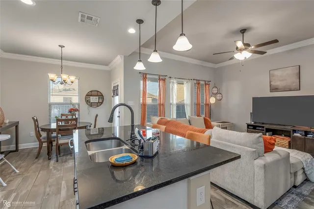 a kitchen with stainless steel appliances granite countertop a stove a sink a dining table and chairs with wooden floor