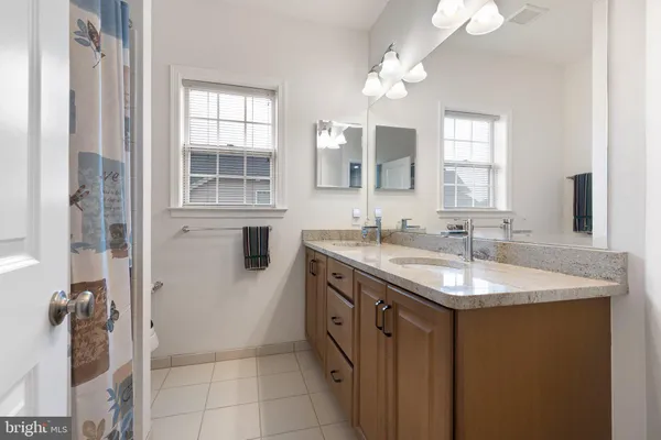 a bathroom with a granite countertop sink a mirror and a shower
