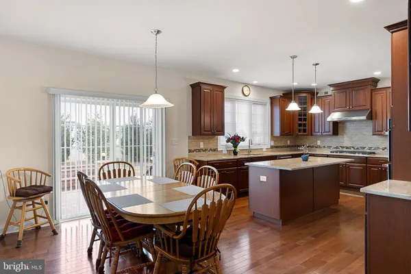 a kitchen with granite countertop a dining table chairs stainless steel appliances and cabinets