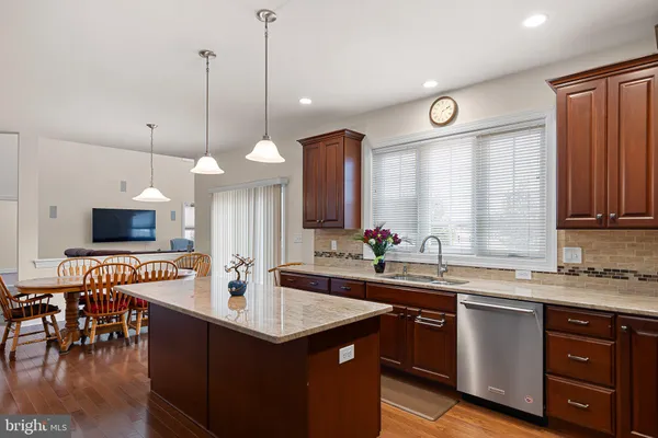 a kitchen with kitchen island granite countertop a sink a counter space appliances and cabinets