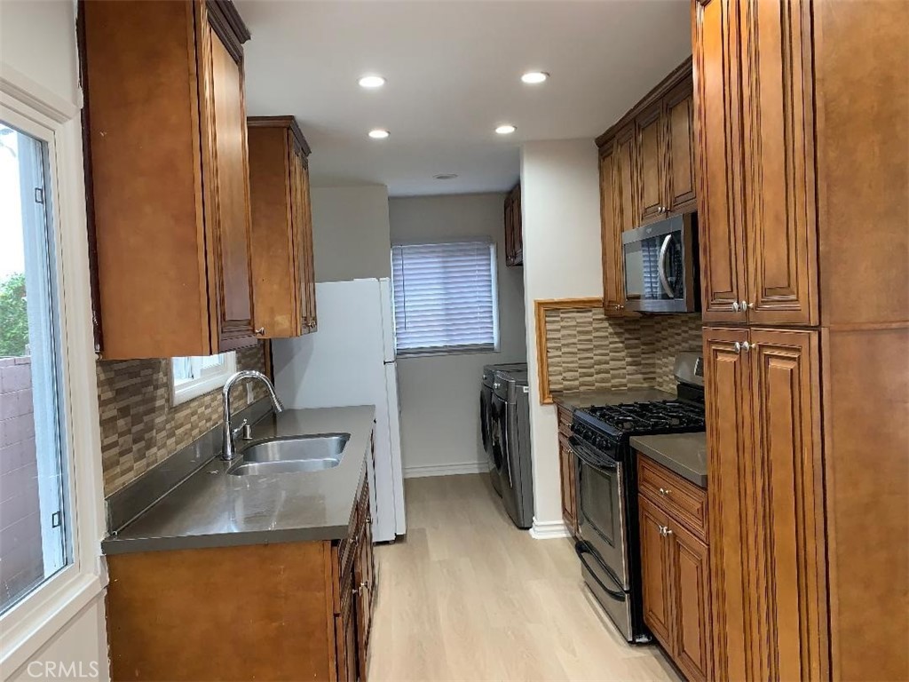 18233 Welby Way Reseda, CA 91335 - Photo 6 of 15 a kitchen with stainless steel appliances granite countertop a sink stove and refrigerator
