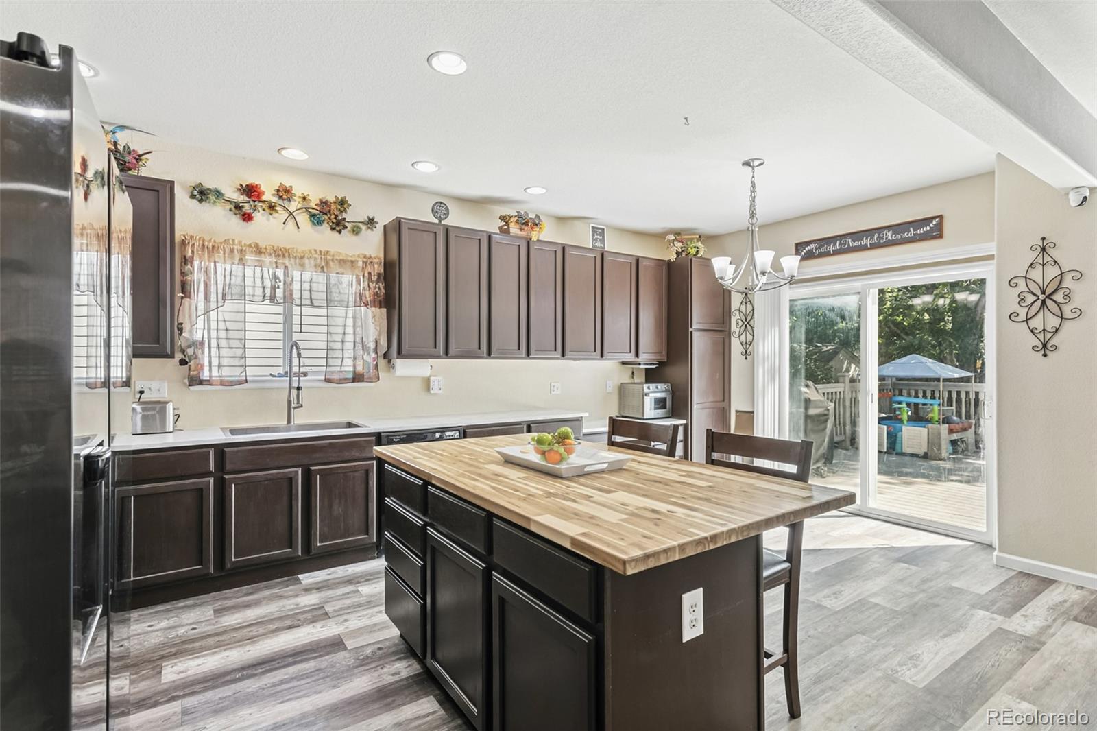 334 Octillo Street Brighton, CO 80601 - Photo 7 of 39 a kitchen with a stove a sink dishwasher and a refrigerator with wooden floor