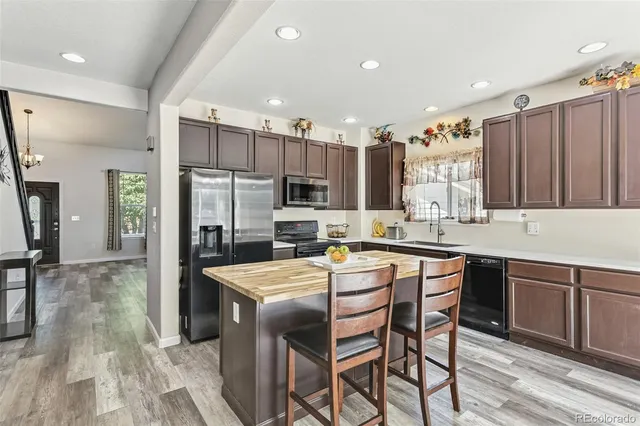 a kitchen with stainless steel appliances granite countertop a table chairs sink refrigerator and microwave
