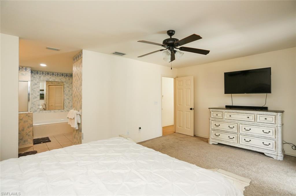 7775 Scarlet Court Naples, FL 34104 - Photo 19 of 30 Bedroom with connected bathroom, ceiling fan, and light carpet