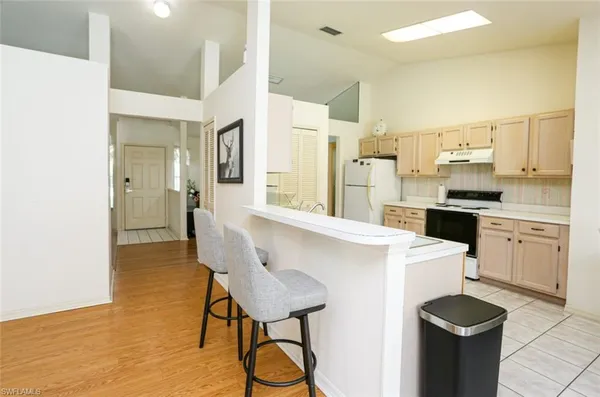 a kitchen with stainless steel appliances a stove a refrigerator and white cabinets with wooden floor