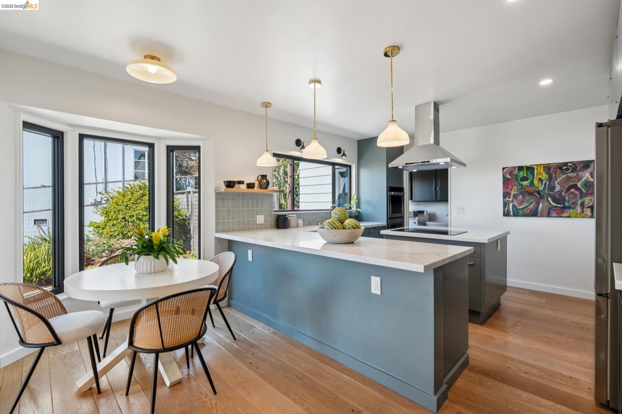 38 Highgate Road Kensington, CA 94707 - Photo 15 of 78 Kitchen featuring wood-finish flooring, a kitchen island with light countertops, stainless steel range hood, built-in oven, and a bay window