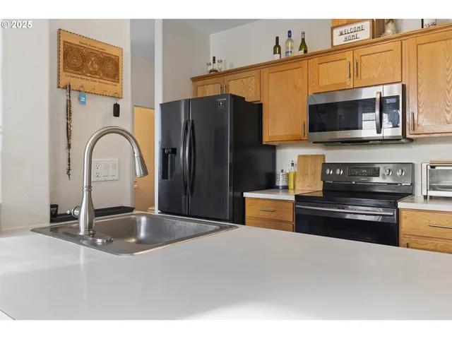a kitchen with stainless steel appliances granite countertop a refrigerator a stove top oven and a sink