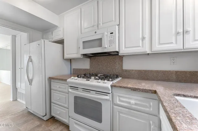 a kitchen with white cabinets and refrigerator
