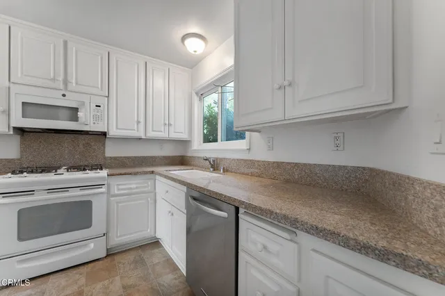 a kitchen with granite countertop white cabinets and white appliances