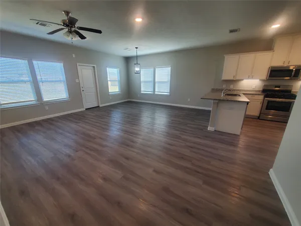 an empty room with wooden floor and ceiling fan