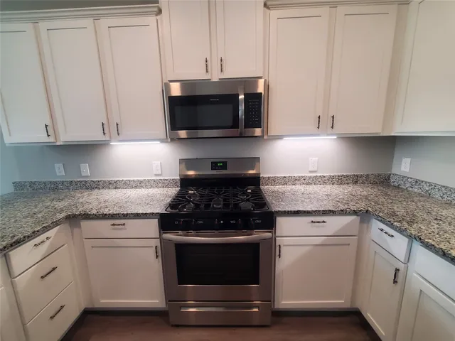 a kitchen with white cabinets and appliances