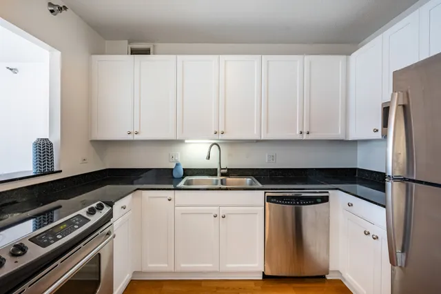 a kitchen with granite countertop white cabinets and stainless steel appliances
