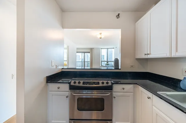 a kitchen with granite countertop white cabinets and a stove top oven