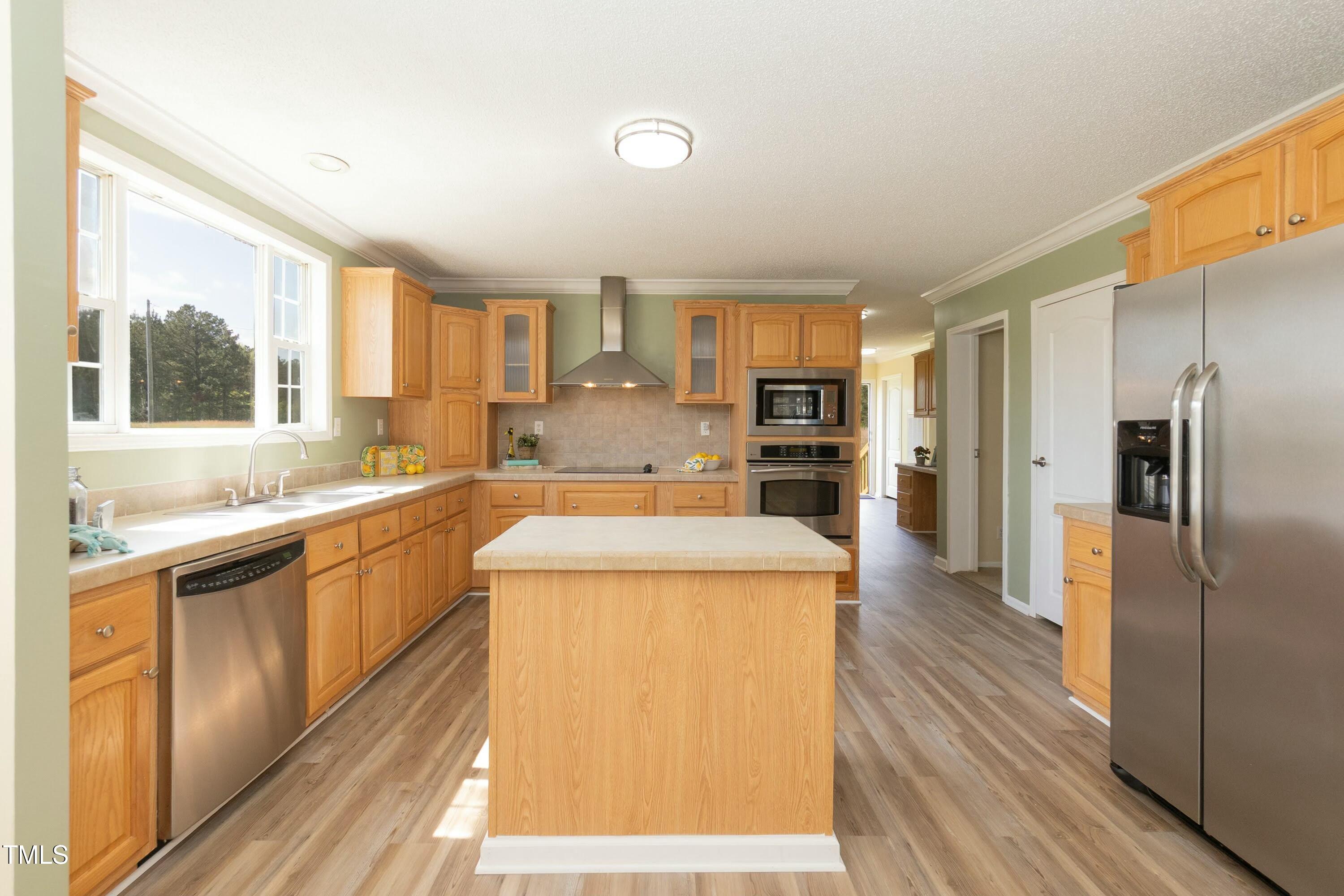 660 Our Way Linden, NC 28356 - Photo 12 of 36 a kitchen with stainless steel appliances granite countertop a refrigerator a sink dishwasher a stove and white countertops with wooden floor