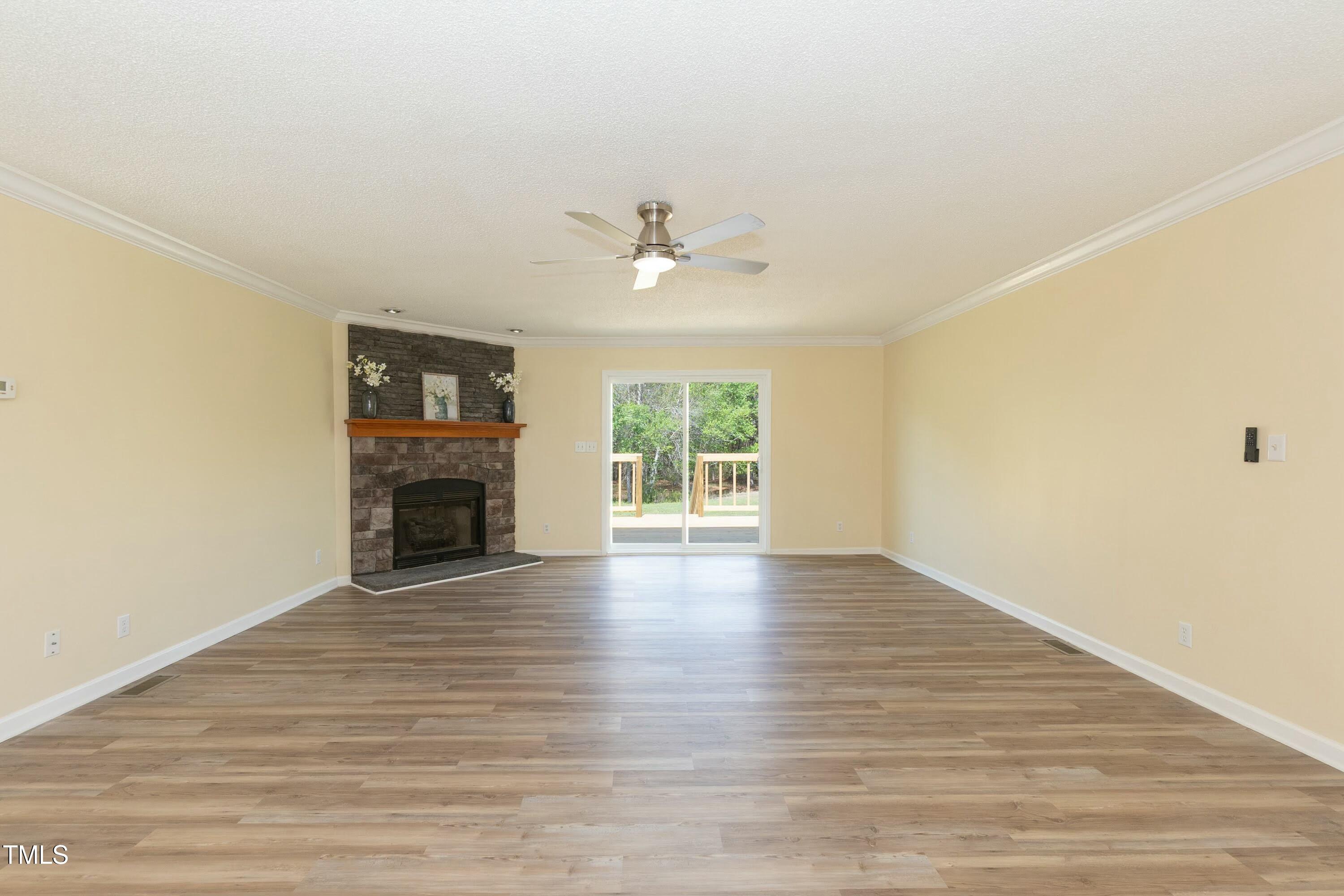 660 Our Way Linden, NC 28356 - Photo 5 of 36 an empty room with wooden floor fireplace and windows
