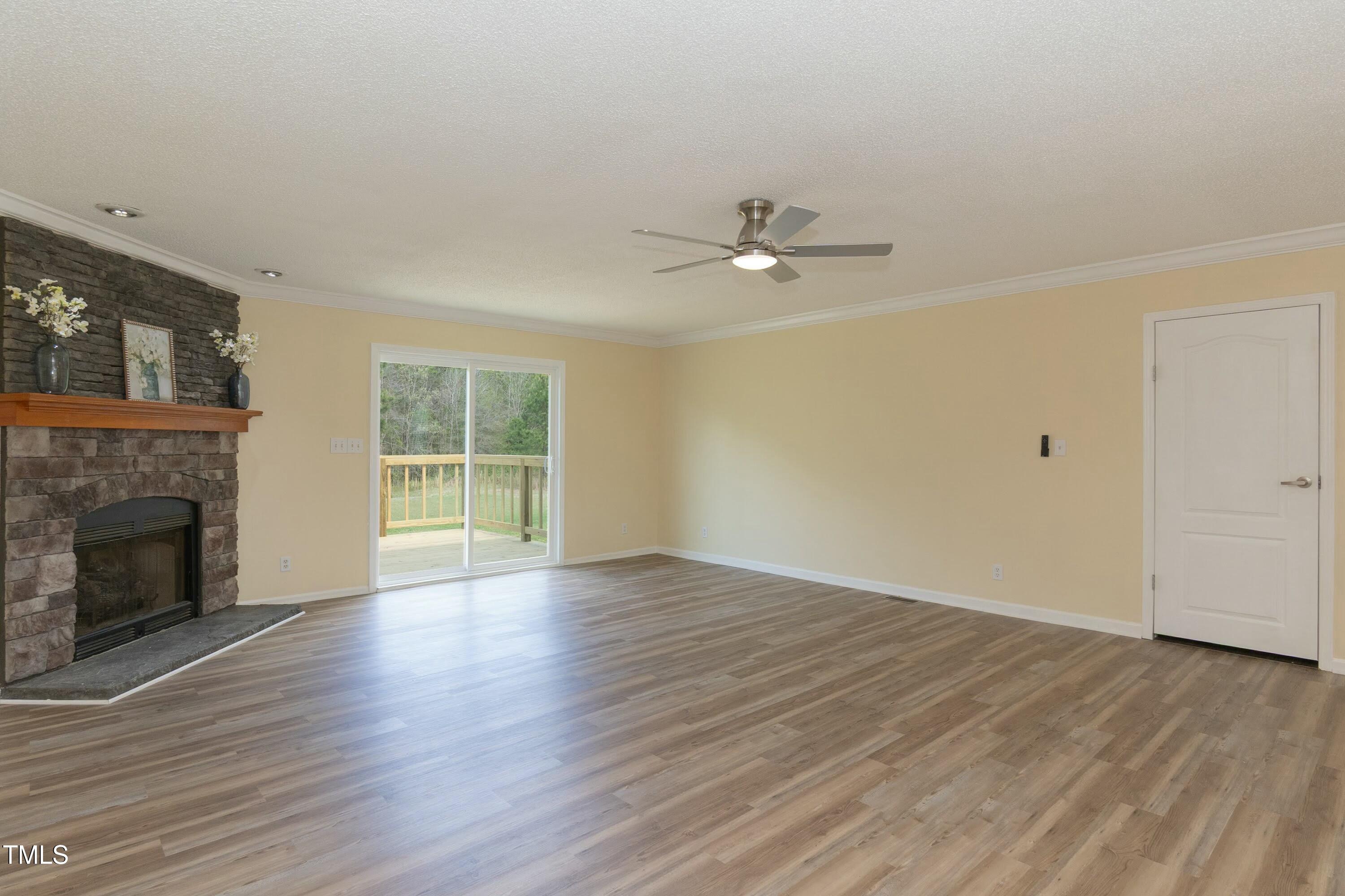 660 Our Way Linden, NC 28356 - Photo 7 of 36 an empty room with wooden floor fireplace and windows