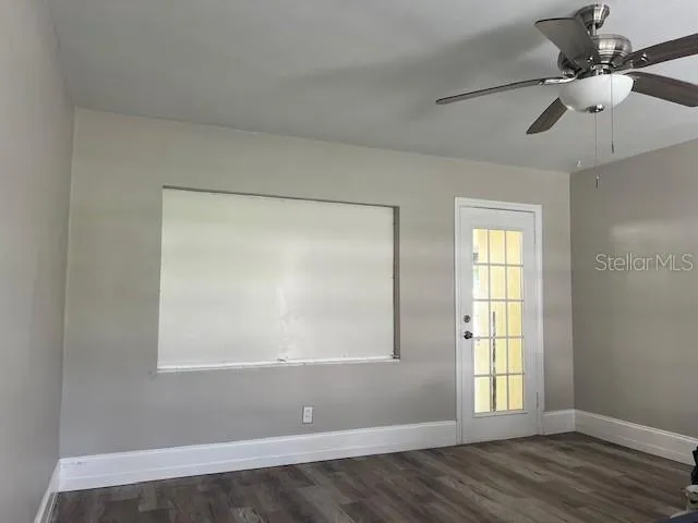 a view of empty room with wooden floor and fan