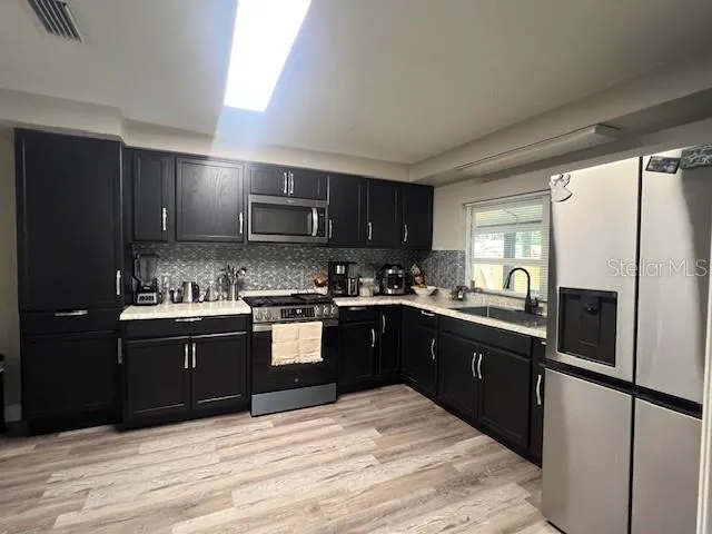 a kitchen with stainless steel appliances granite countertop a refrigerator a sink dishwasher a stove top oven and a refrigerator