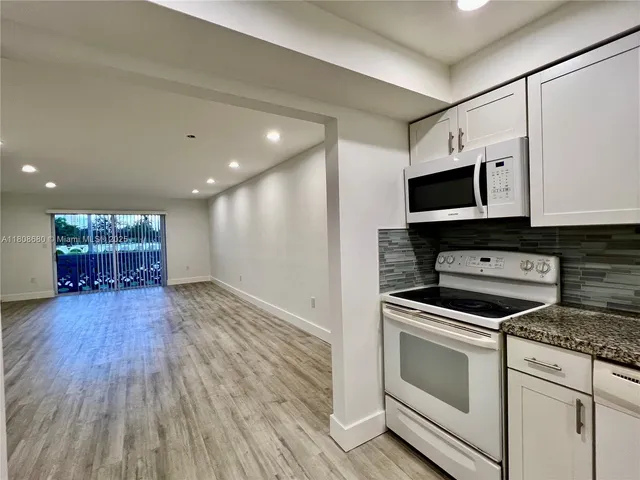 a kitchen with kitchen island granite countertop a stove and a microwave