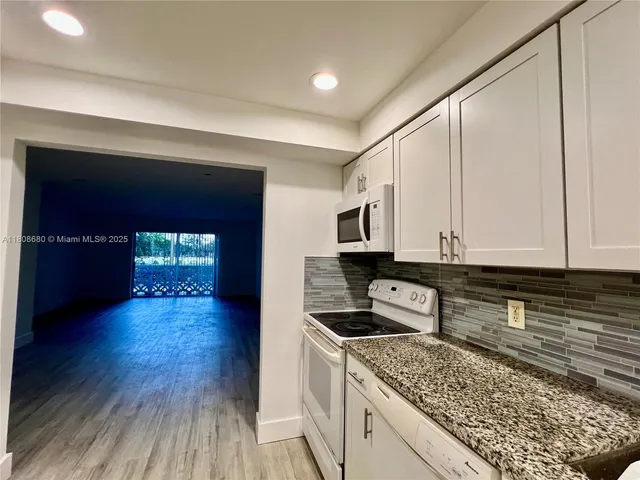 a kitchen with stainless steel appliances granite countertop a stove a sink and white cabinets