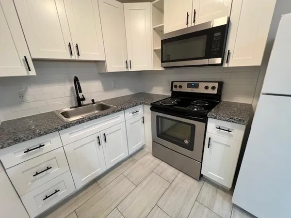 a kitchen with white cabinets and black appliances