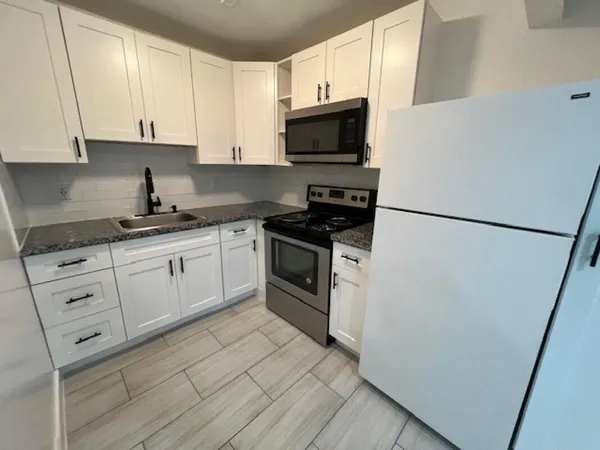 a kitchen with white cabinets and white appliances