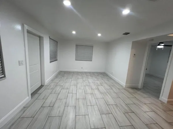 an empty room with wooden floor and windows