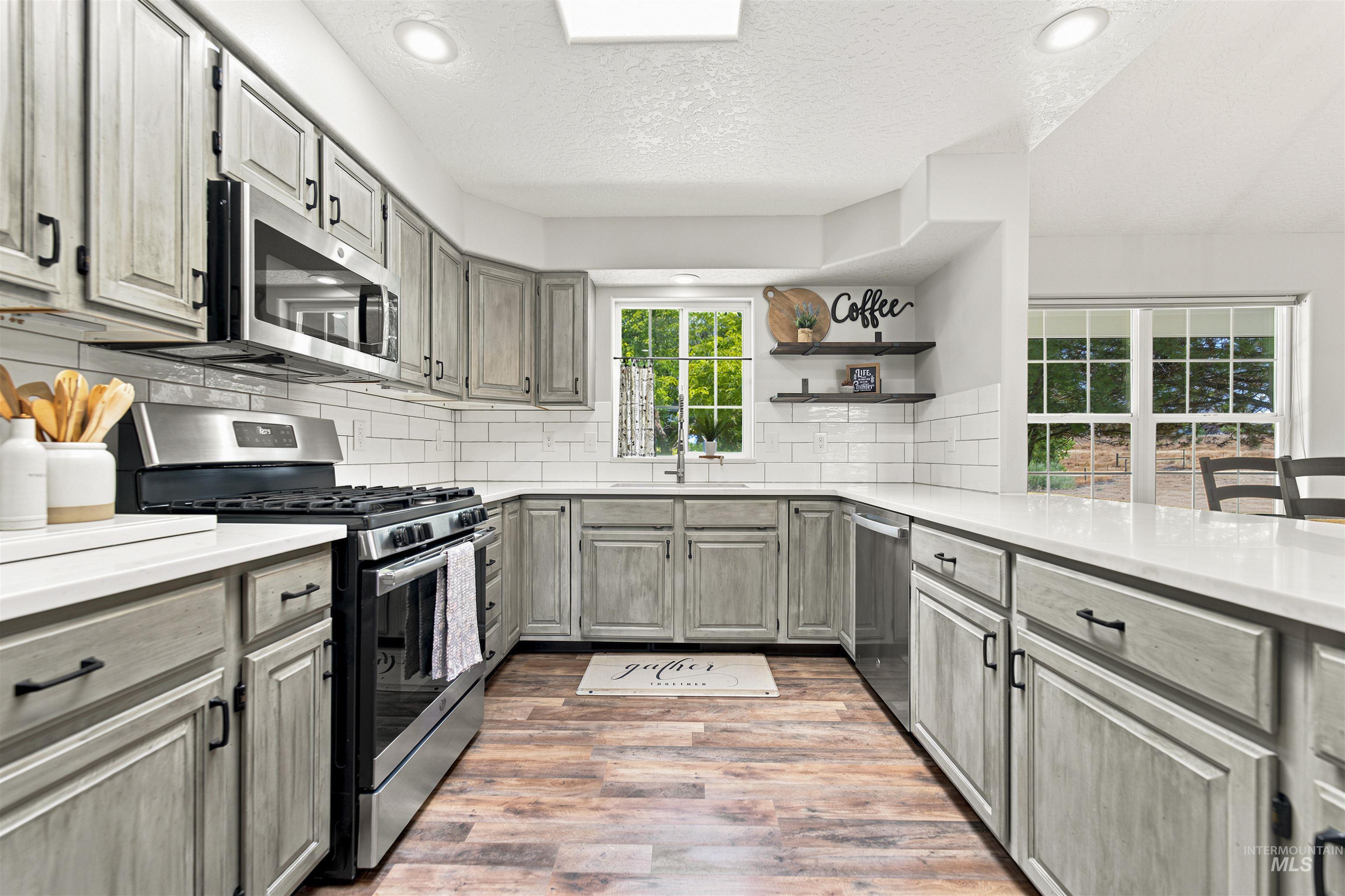 24864 Coventry Drive Caldwell, ID 83607 - Photo 12 of 49 Kitchen featuring wood-finish flooring, light grey cabinetry, white countertops, and a white subway tile backsplash