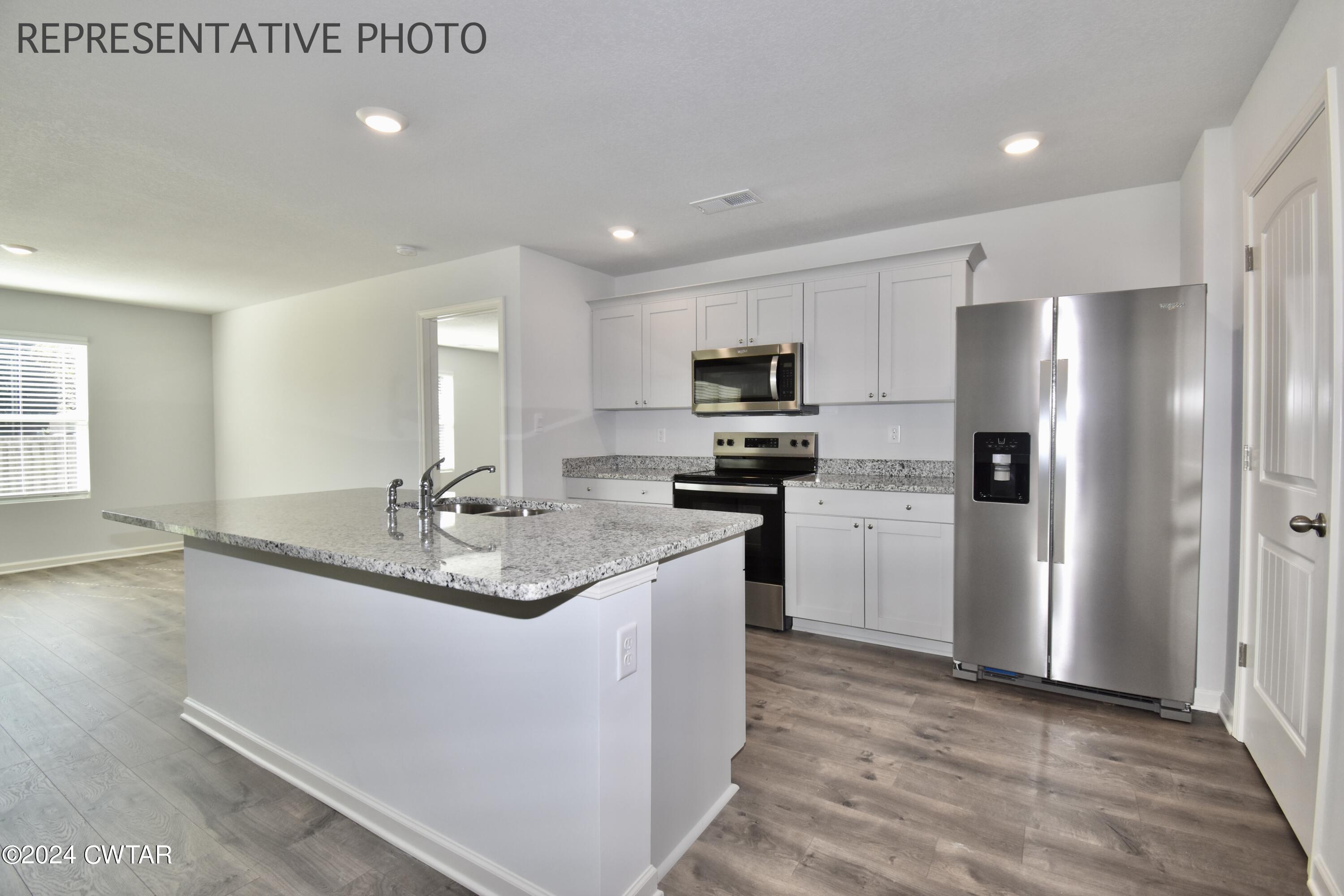 61 Vintage Grove Road Jackson, TN 38305 - Photo 4 of 25 a kitchen with kitchen island granite countertop stainless steel appliances a sink a stove a refrigerator cabinets and a window