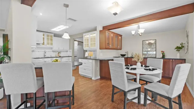 a kitchen with stainless steel appliances kitchen island granite countertop a dining table chairs and a refrigerator