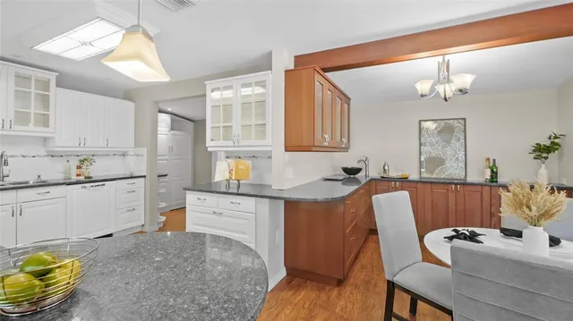 a kitchen with stainless steel appliances granite countertop a sink dishwasher a stove a dining table and chairs with wooden floor