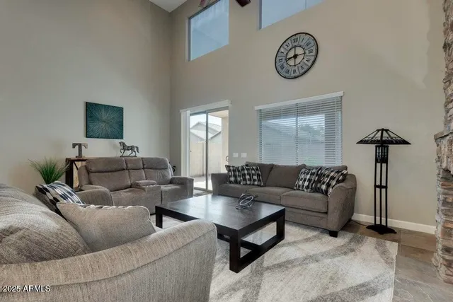 a living room with furniture a clock on wall and a window