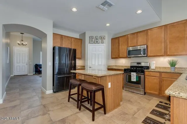 a kitchen with granite countertop a refrigerator and a stove top oven