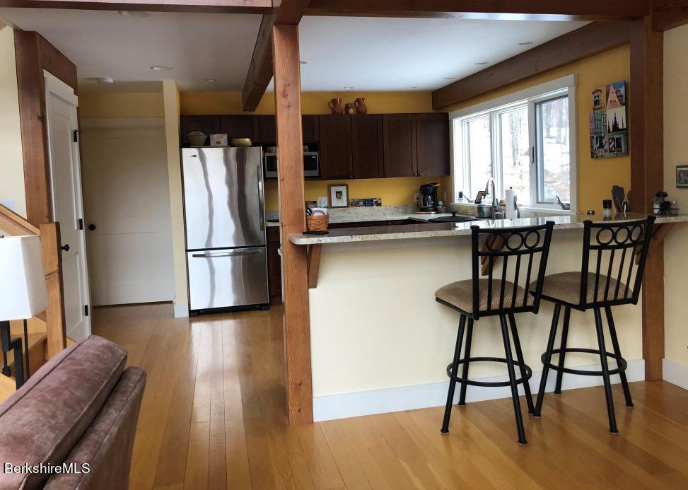 469 Boulger Road Stamford, VT 05352 - Photo 8 of 37 a kitchen with stainless steel appliances granite countertop a stove top oven a refrigerator a dining table and chairs with wooden floor